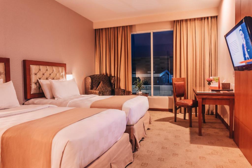 a hotel room with two beds and a flat screen tv at Swiss-Belinn SKA Pekanbaru in Pekanbaru