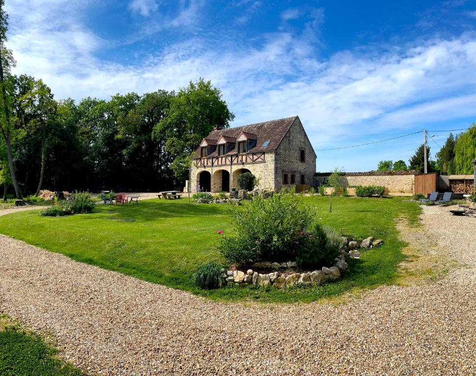 an old stone building on a grassy field with a house at Architecte Les 3 arches de Dormelles in Dormelles