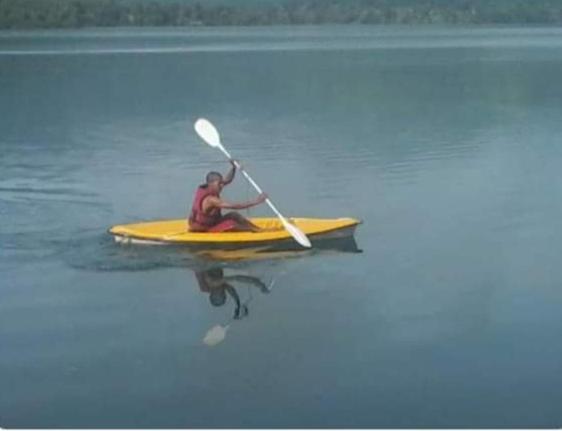 un hombre sentado en un kayak amarillo en el agua en Omkar Agro Tourism & Resort, en Mahabaleshwar