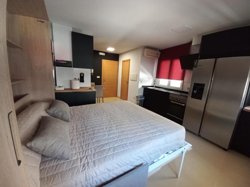 a bedroom with a white bed and a refrigerator at Estudio en Ribeira in Ribeira