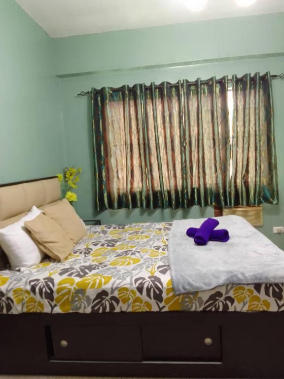 Un dormitorio con una cama con un animal de peluche púrpura. en Affordable Transient in Valley Golf near Emperor Events Place, en Cainta