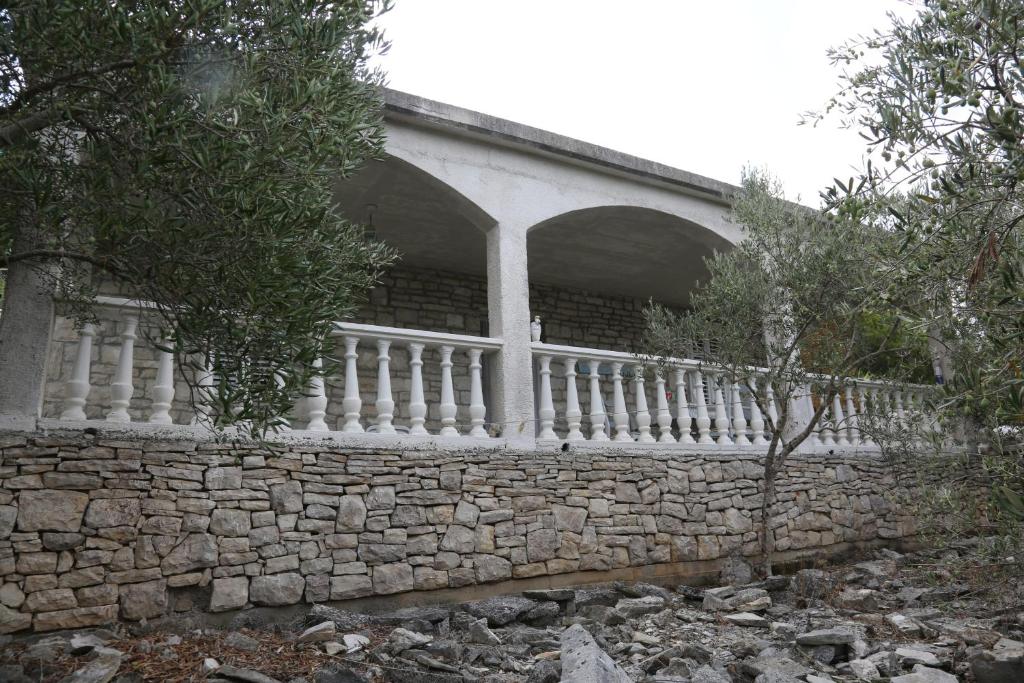 eine steinerne Mauer mit einem weißen Zaun in der Unterkunft Seaside holiday house Prigradica, Korcula - 18002 in Blato