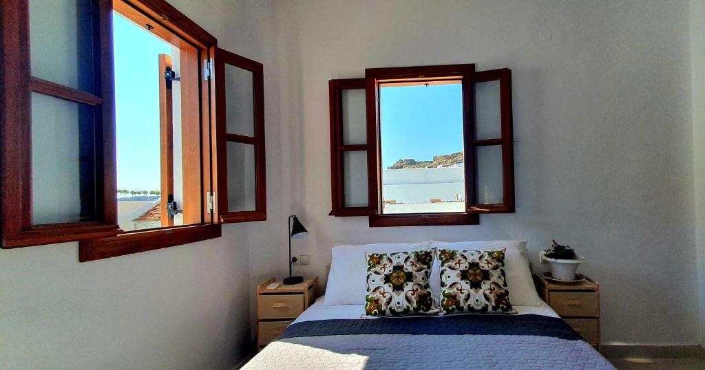 um quarto com uma cama com duas almofadas e duas janelas em The Olive Tree Villa Lindos em Lindos