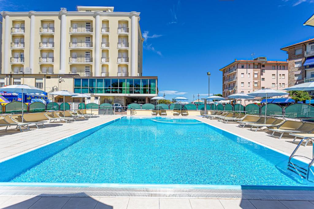 uma piscina com cadeiras e guarda-sóis em frente a um edifício em Hotel San Giorgio em Cesenatico