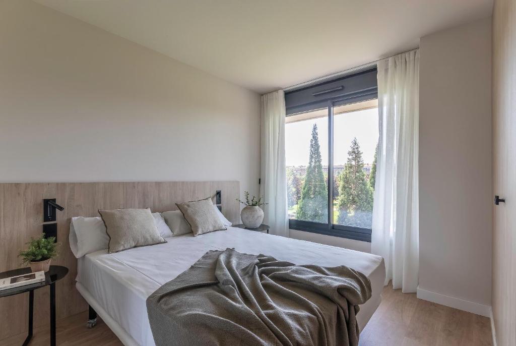 a bedroom with a large bed and a large window at Apartamentos Líbere Pamplona Yamaguchi in Pamplona