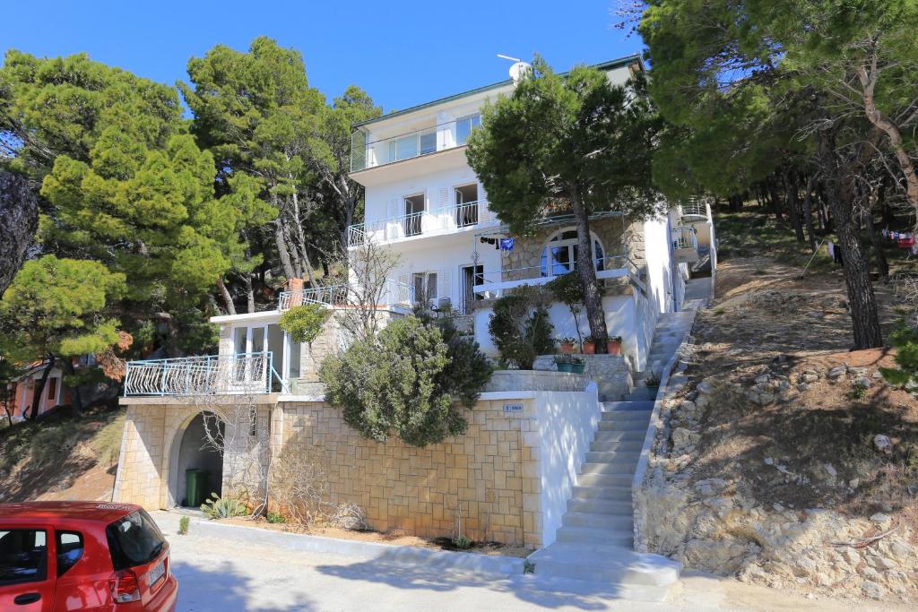a house on a hill with a red car parked in front at Rooms with a parking space Brela, Makarska - 17281 in Brela