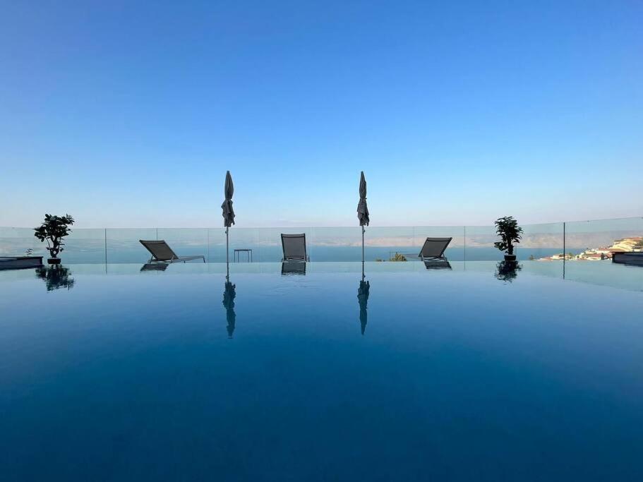 a pool with chairs and the ocean in the background at Villa-SELAVI 3 unit complex with infinity pool in Tiberias