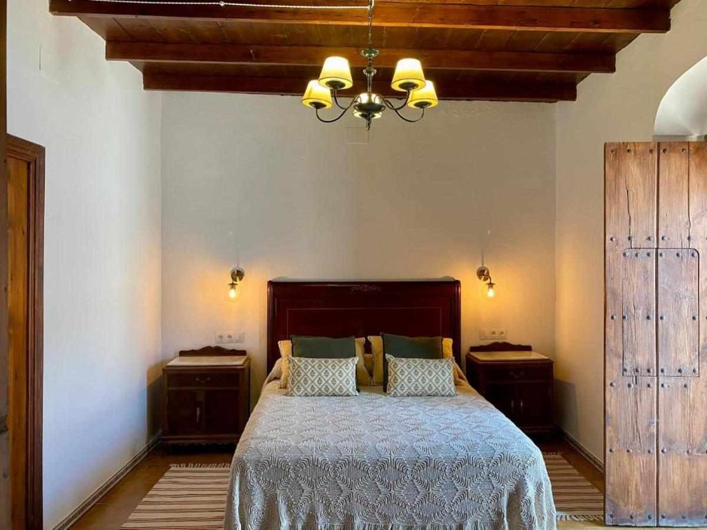 ein Schlafzimmer mit einem großen Bett und einem Kronleuchter in der Unterkunft La Casona de la Sierra in Higuera de la Sierra