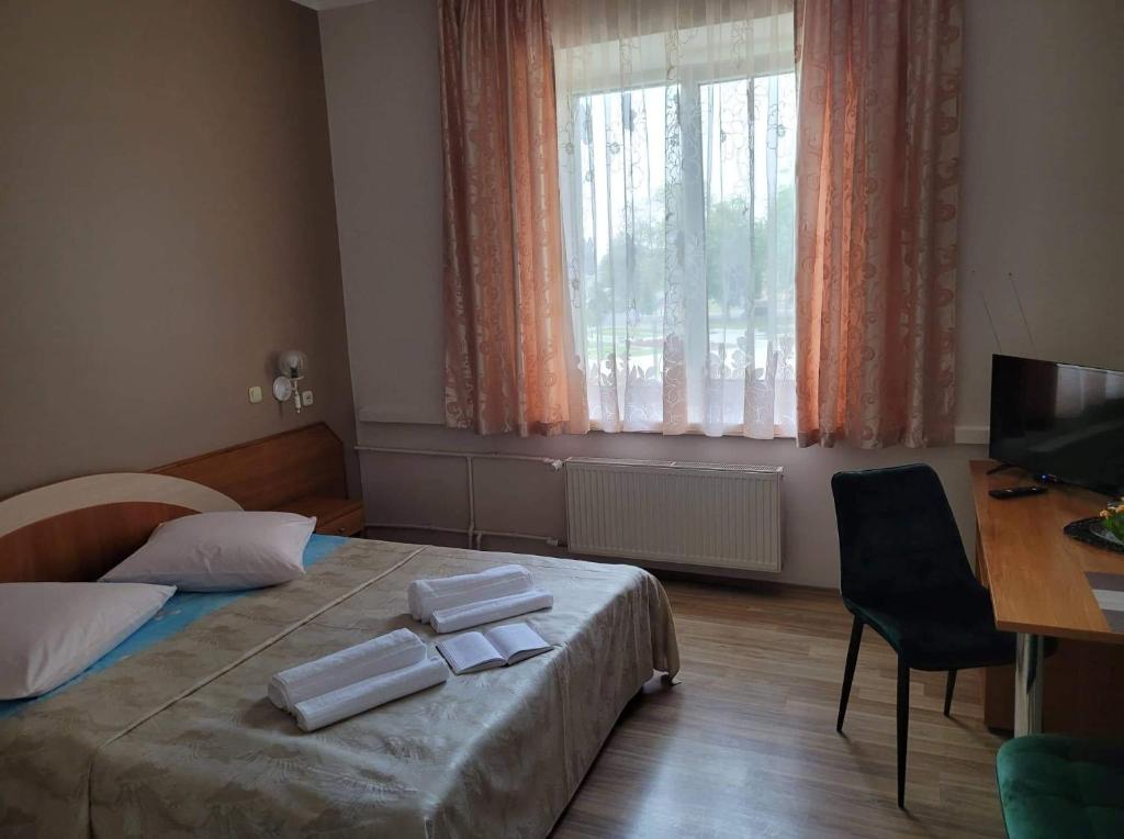 Schlafzimmer mit einem Bett, einem Schreibtisch und einem Fenster in der Unterkunft Viešbutis RASA in Raseiniai