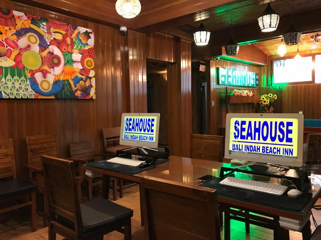 twee computermonitors op een tafel in een restaurant bij Seahouse Bali Indah Beach Inn in Kuta