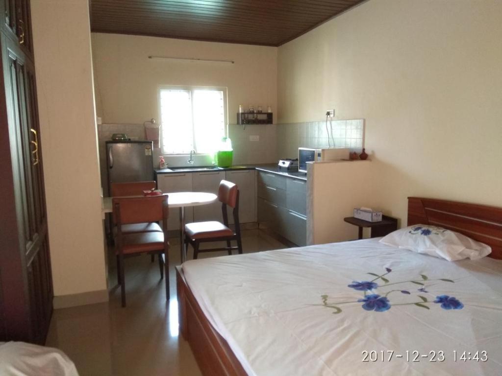 Cet appartement comprend une chambre avec un lit et une table ainsi qu'une cuisine. dans l'établissement Casa Riverdale Farm Stay, à Vallikavungal