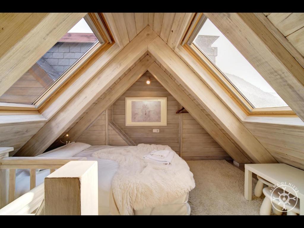 a attic room with a bed and a window at VARRADOS de Alma de Nieve in Naut Aran