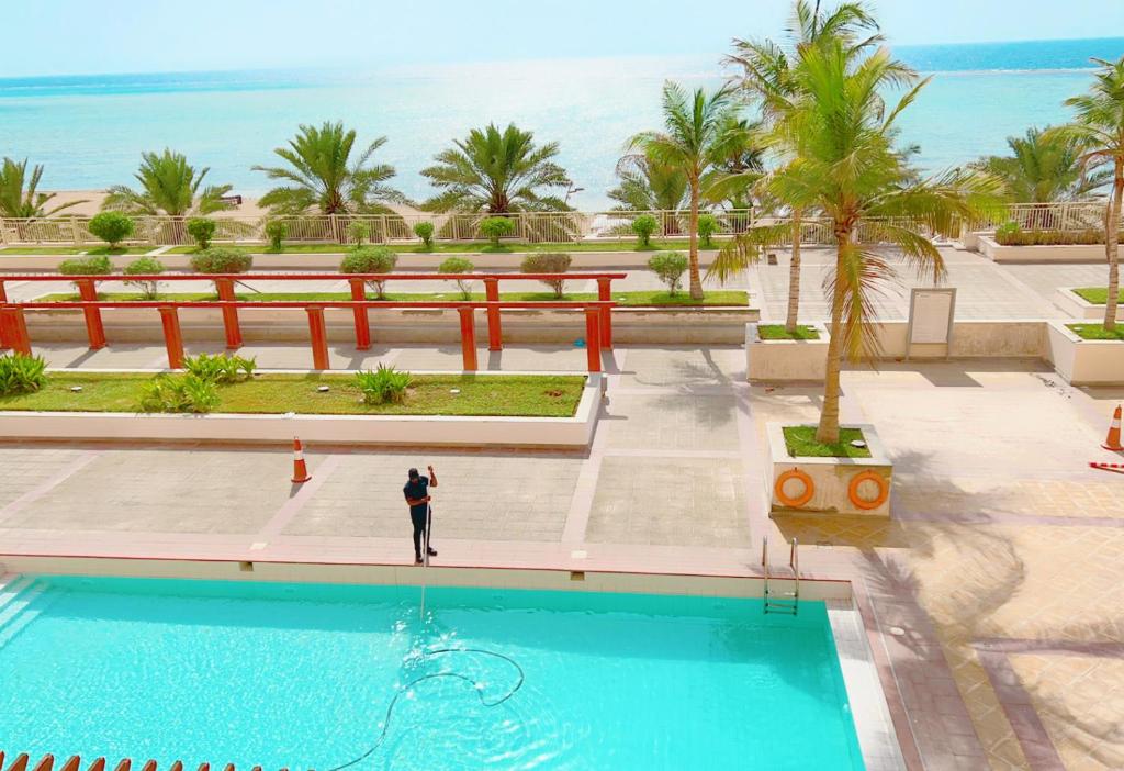 a man standing next to a swimming pool at a resort at موج البحر ابراج الشاطئ مدينه الملك عبدالله الاقتصاديه عوائل فقط in King Abdullah Economic City