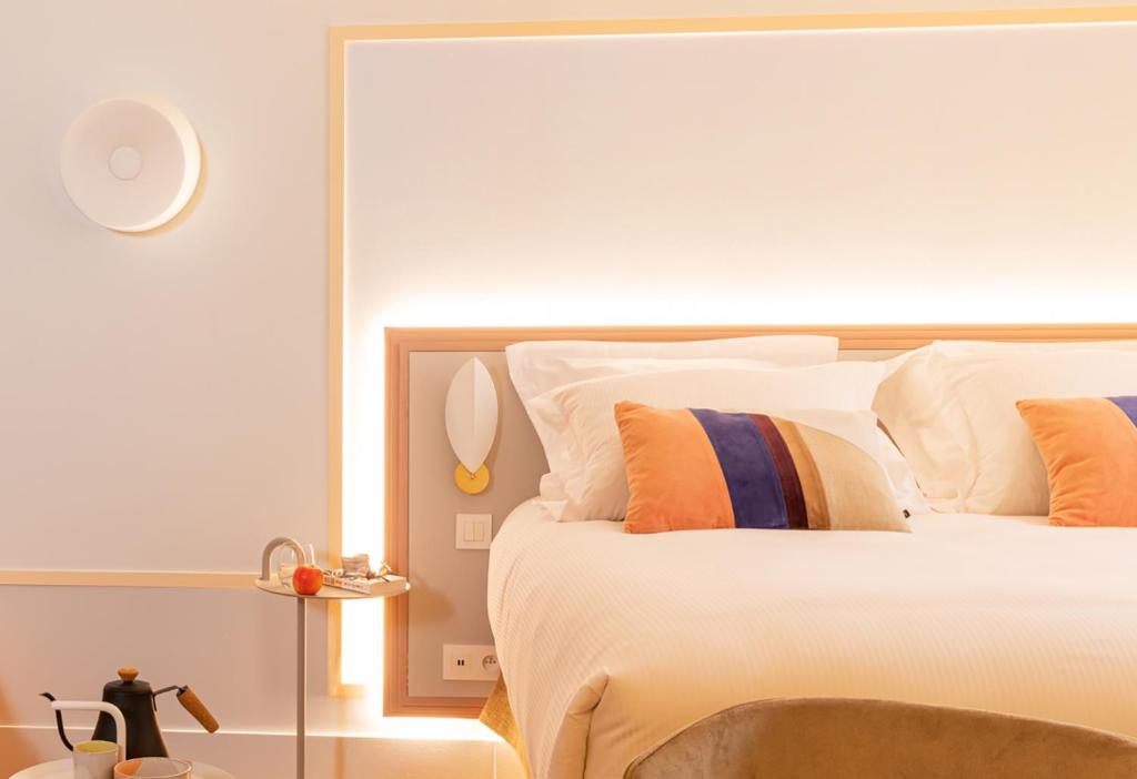 a bedroom with a large bed with orange and blue pillows at Aiden by Best Western Clermont-Ferrand - Le Magnetic Hotel & Spa in Clermont-Ferrand