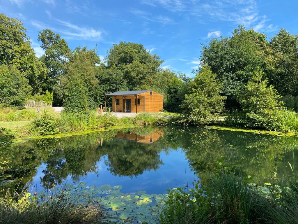 un pequeño edificio de madera junto a un lago en Kingfisher Cabin - Wild Escapes Wrenbury off grid glamping - ages 12 and over, en Baddiley