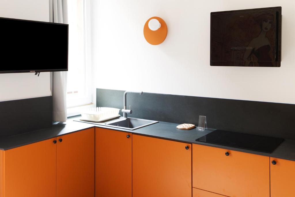 kuchnia z pomarańczowymi i czarnymi szafkami oraz zlewem w obiekcie JOIVY Smart 1-bed with modern amenities w Mediolanie
