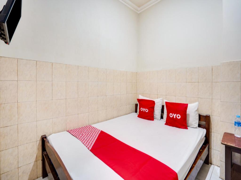 Cama en habitación con 2 almohadas rojas en OYO Life 91511 Ampel Residence Syariah, en Surabaya