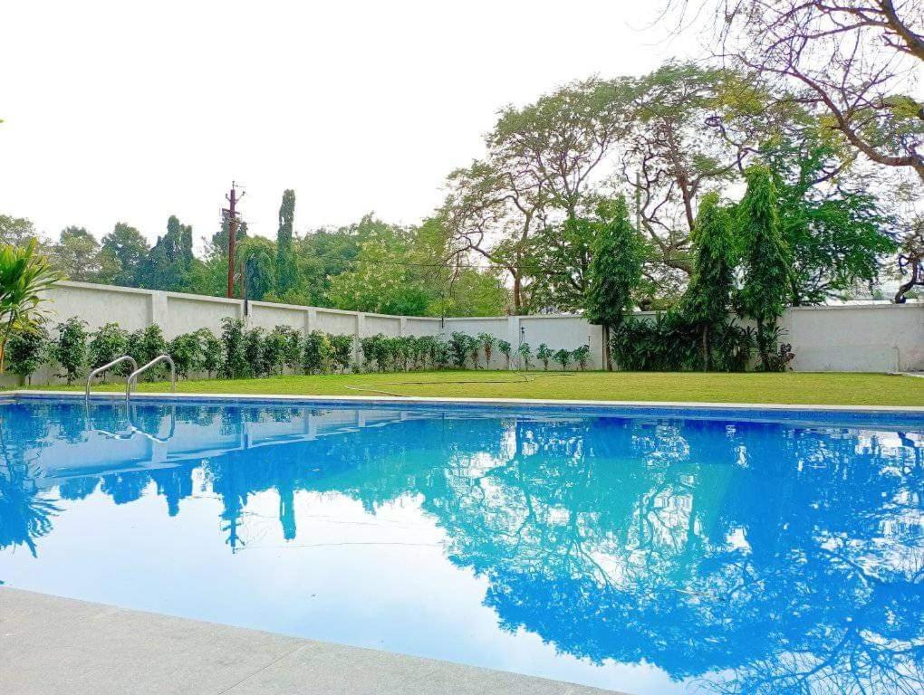 a swimming pool with blue water in a yard at HOTEL SHREE VILLA in Harsola