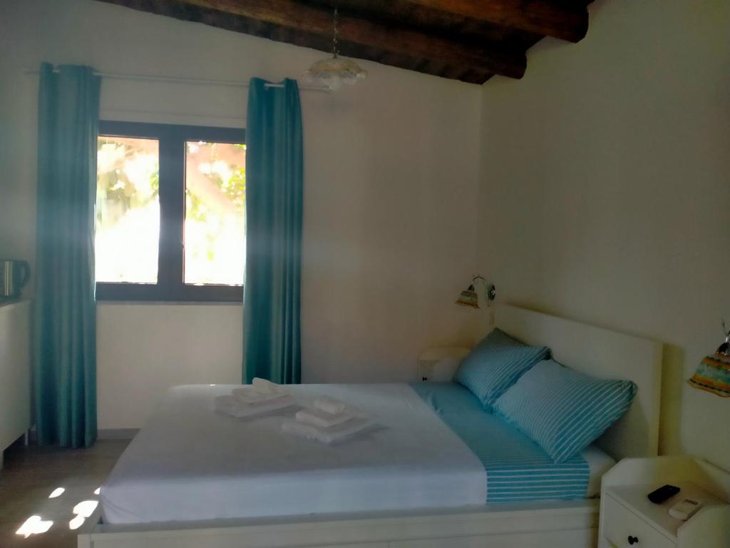1 dormitorio con 1 cama con cortinas azules y ventana en Il Siriaco en Calatabiano