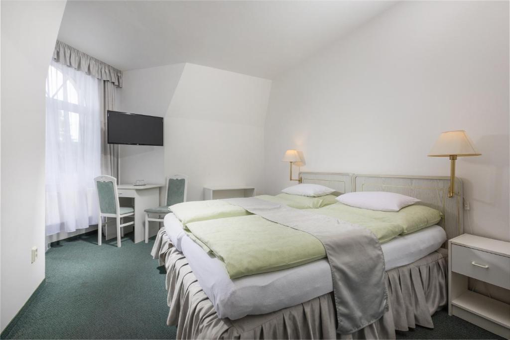 マリアーンスケー・ラーズニェにあるHotel Ferdinandのベッド2台とデスクが備わるホテルルームです。
