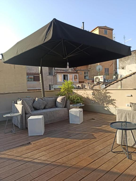a large black umbrella on a deck with a couch and tables at Nikis Collection Trastevere in Rome