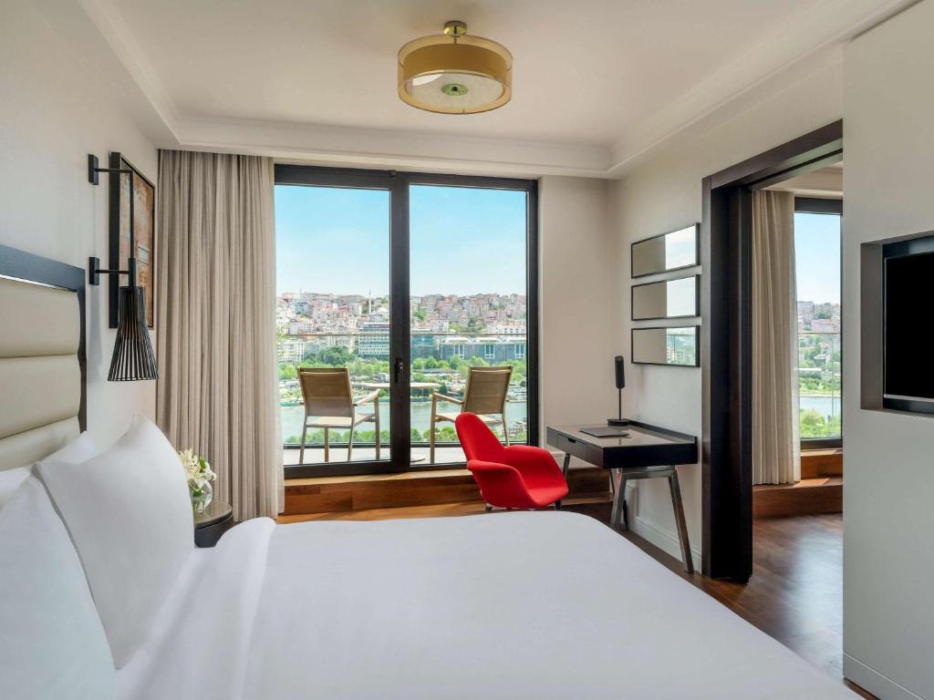 a hotel room with a bed and a desk with a red chair at Mövenpick Istanbul Hotel Golden Horn in Istanbul