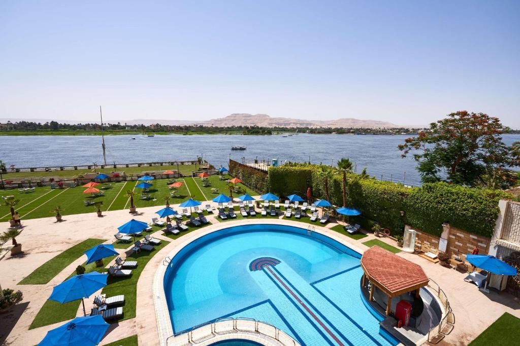 a pool with chairs and umbrellas next to the water at Sonesta St. George Hotel - Convention Center in Luxor