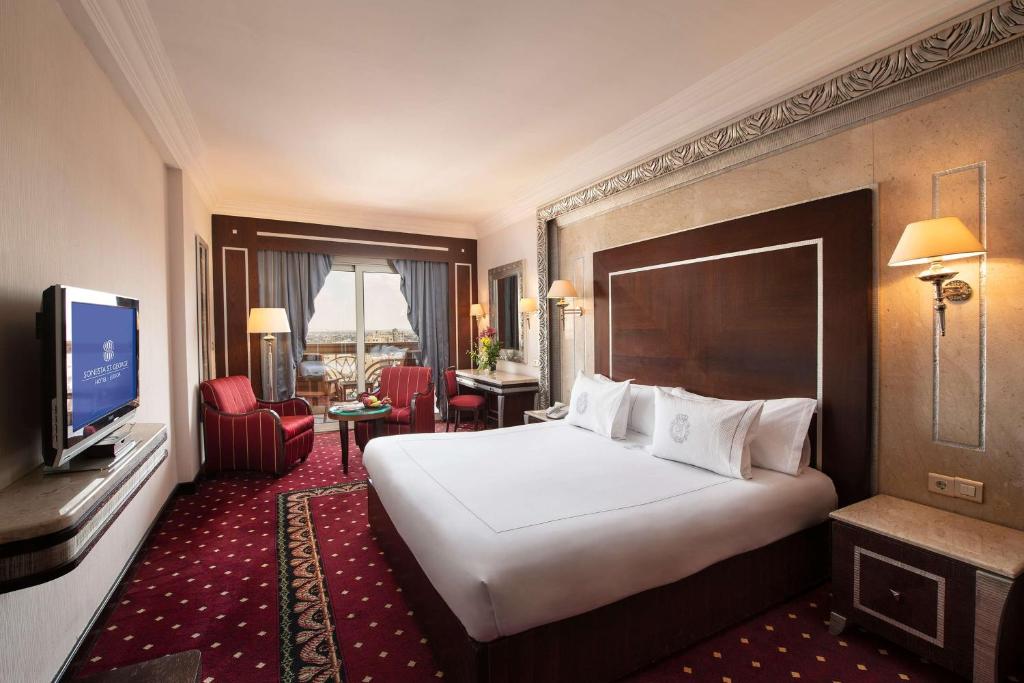 a hotel room with a large bed and a television at Sonesta St. George Hotel - Convention Center in Luxor