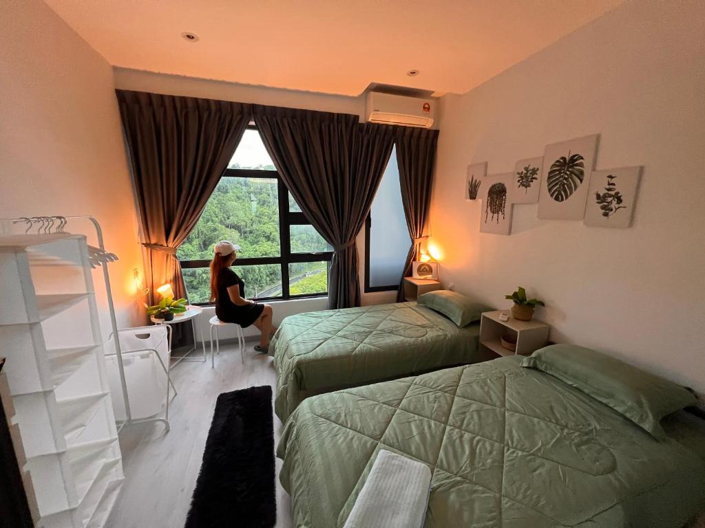 una mujer en una habitación con 2 camas y una ventana en Jesselton Quay Suite by Backyard en Kota Kinabalu