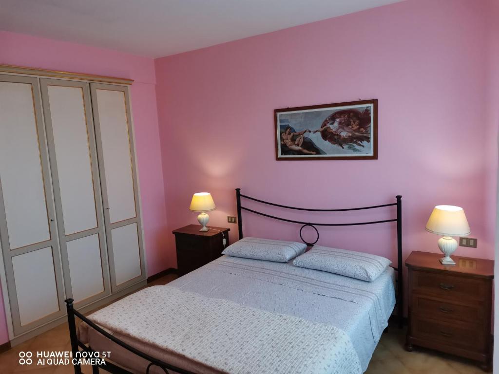 a bedroom with a bed with purple walls and two lamps at Villetta Camelia a due passi da piscina a pagamento in Guamo