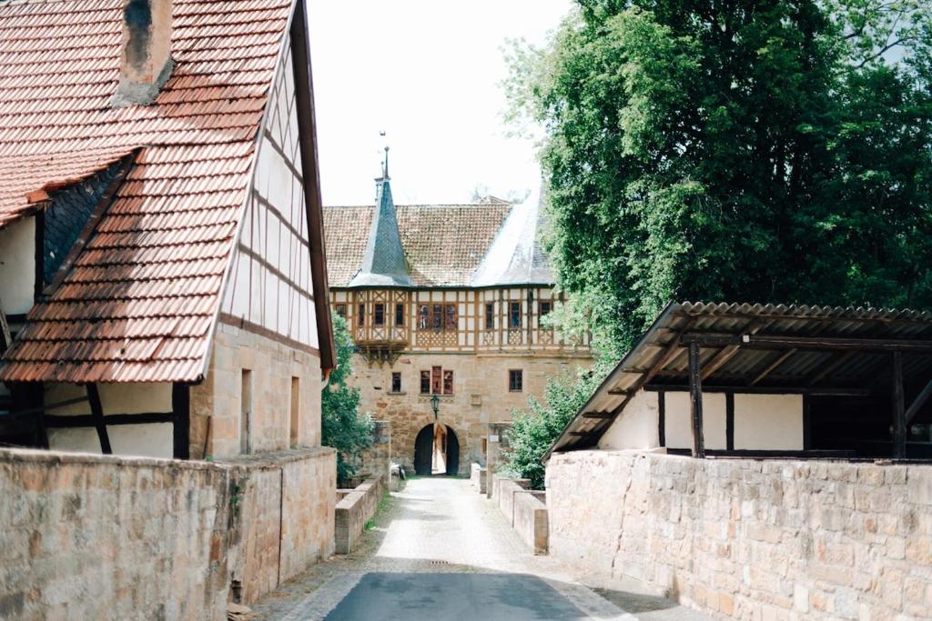 een steegje in een kasteel met een gebouw op de achtergrond bij Urlaub im Wasserschloss Irmelshausen in Höchheim