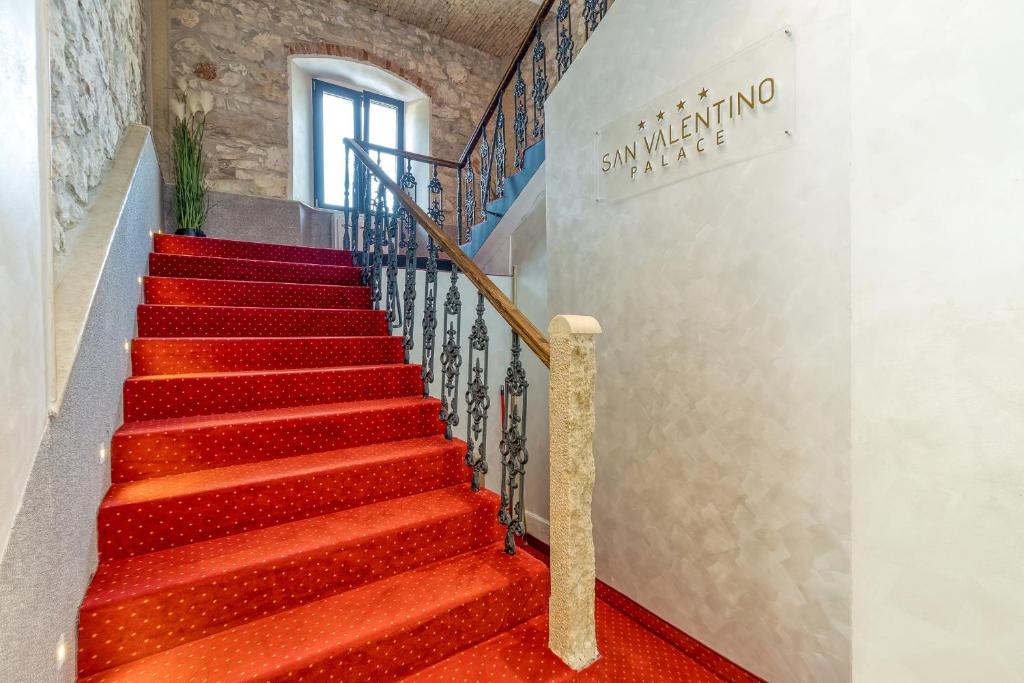 eine Treppe mit rotem Teppichboden und ein Schild an der Wand in der Unterkunft San Valentino Palace in Umag