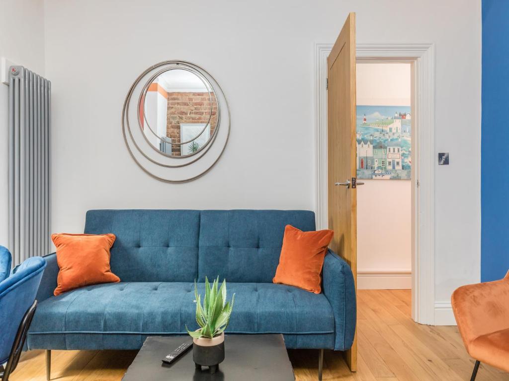 a blue couch in a living room with a mirror at Stylish 2-bedroom flat with patio and garden in Brighton & Hove