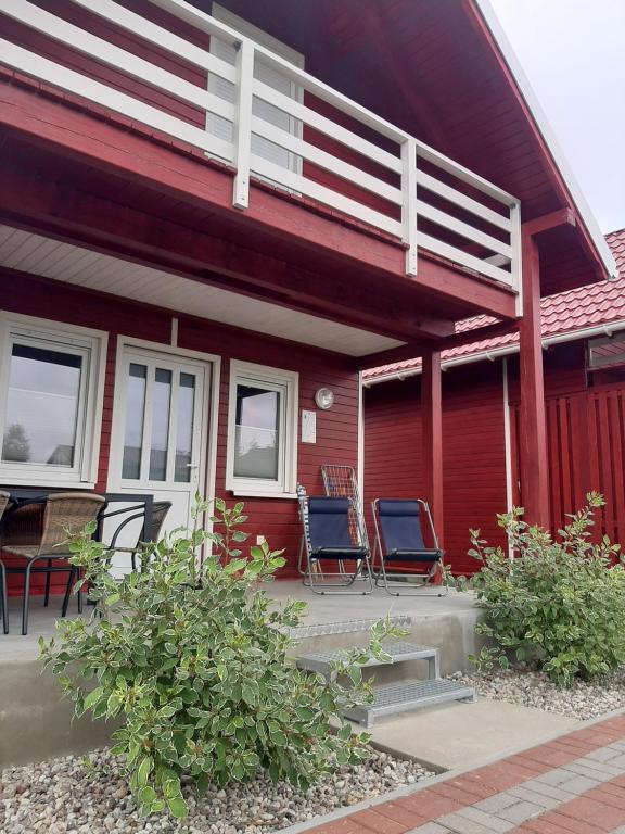 two chairs sitting on the porch of a red house at Osada Szwedzka Domek Plus in Rusinowo