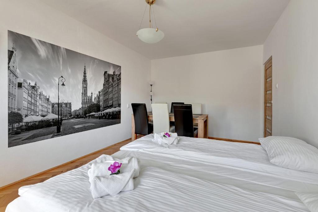Duas camas num quarto com lençóis brancos e flores cor-de-rosa em Wave Apartments - ŻUŁAWIANKA GDAŃSK em Gdansk