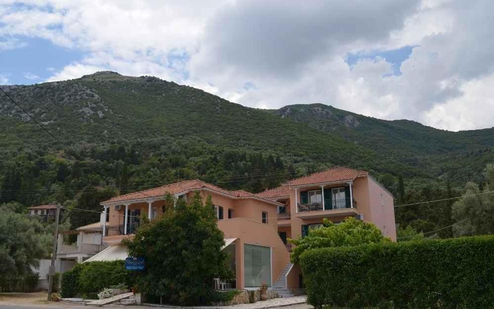 une grande maison avec une montagne en arrière-plan dans l'établissement Odysseia Apartments, à Nikiana