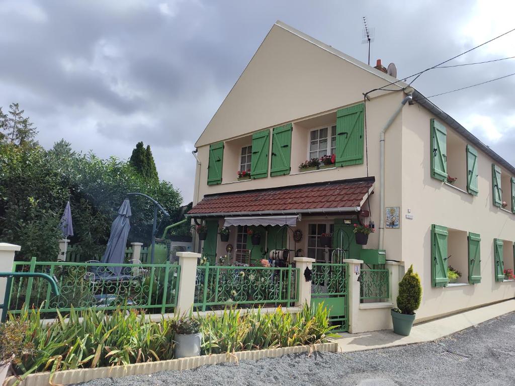 a house with green shutters and a fence at Un Coin de Paradis à Doue , 40 minutes Disneyland in Doue