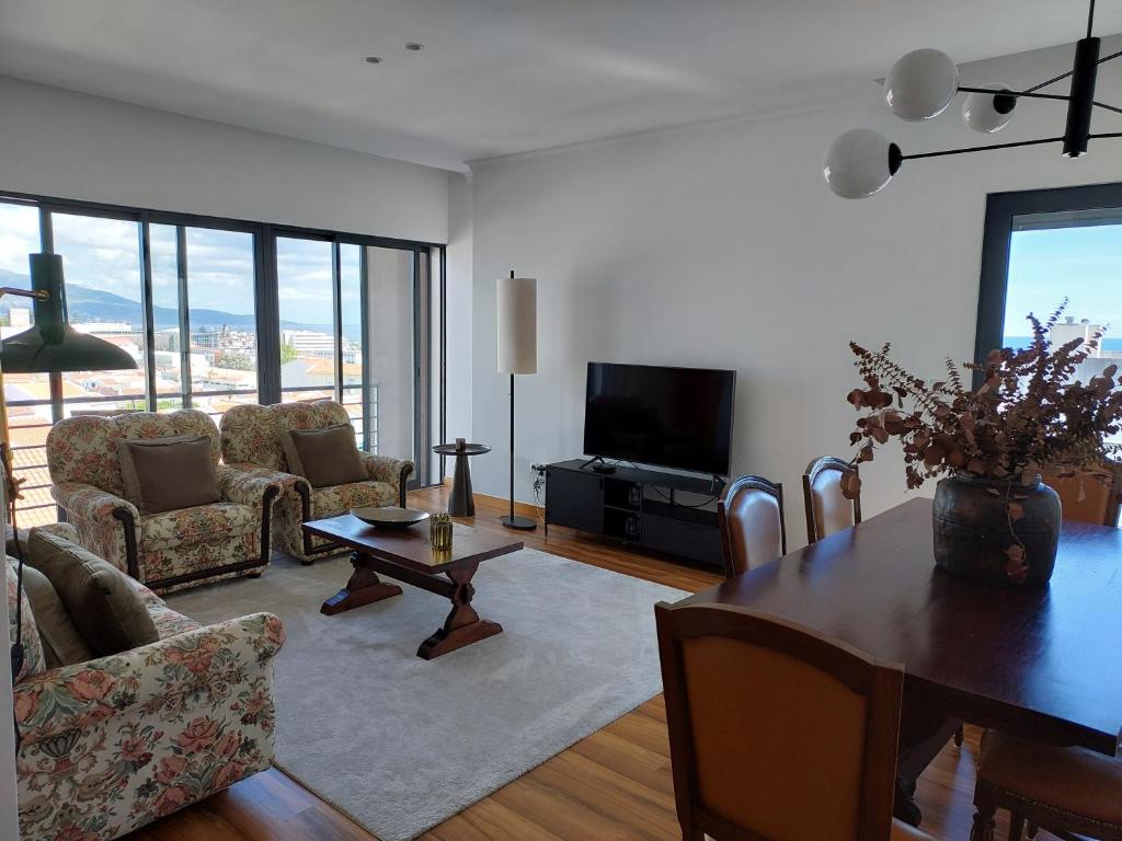 een woonkamer met een tafel en stoelen en een televisie bij Azores Essence - Paim in Ponta Delgada