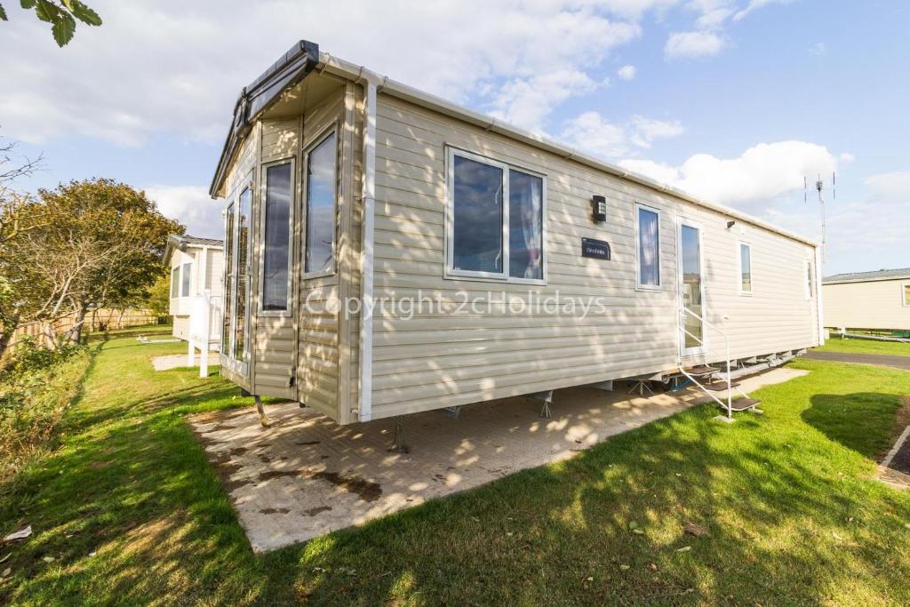 a mobile caravan parked in a yard at 6 Berth Caravan For Hire At Seawick Holiday Park By The Beach Ref 27011hv in Clacton-on-Sea