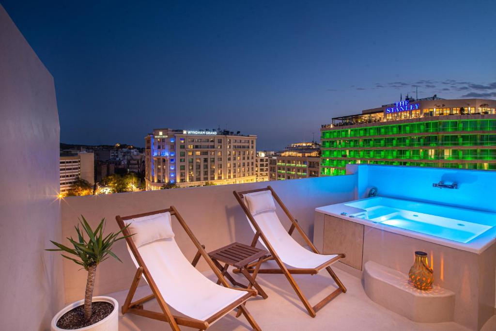 a balcony with three chairs and a hot tub at The Suite Athens in Athens