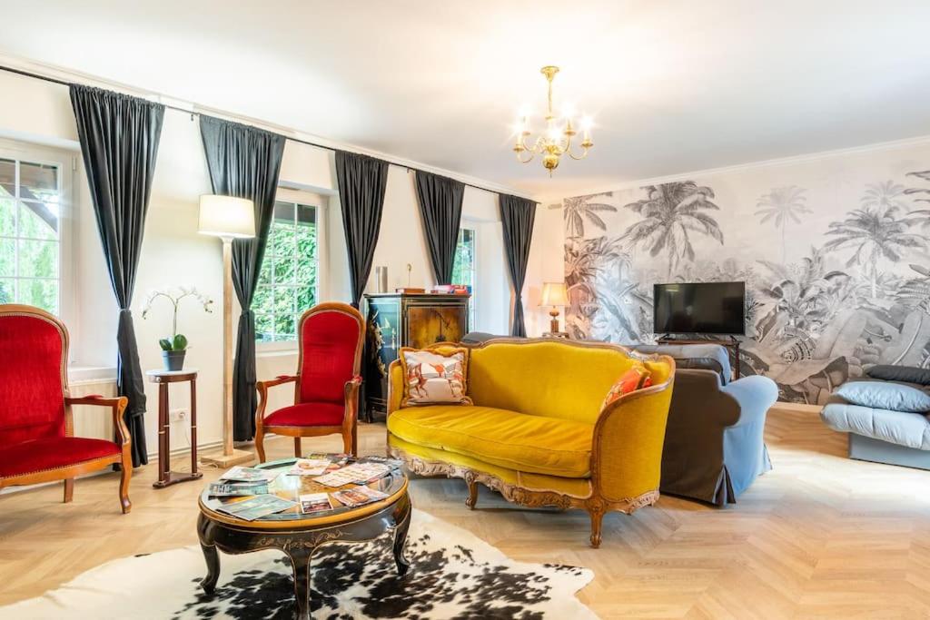 sala de estar con sofá amarillo y sillas rojas en Maison pour les vacances et les événements 12 personnes en La Desverie