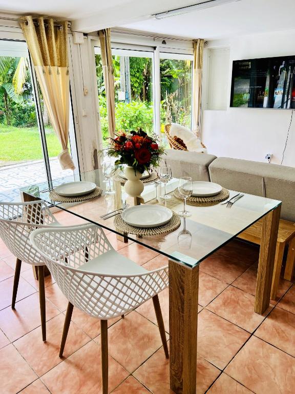 comedor con mesa de cristal y sillas en Appartement de 2 chambres avec jardin et wifi a Petit Bourg, en Petit-Bourg