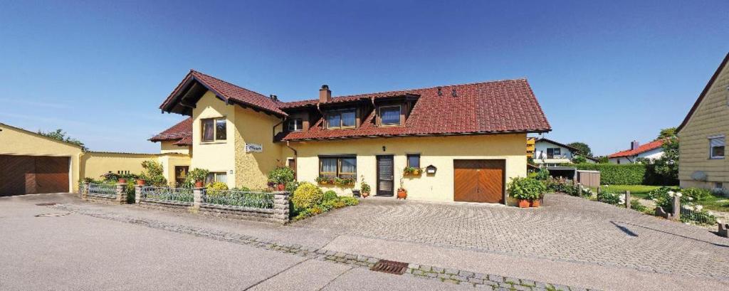 ein gelbes Haus mit rotem Dach und einer Einfahrt in der Unterkunft Haus Hilgarth in Bad Füssing