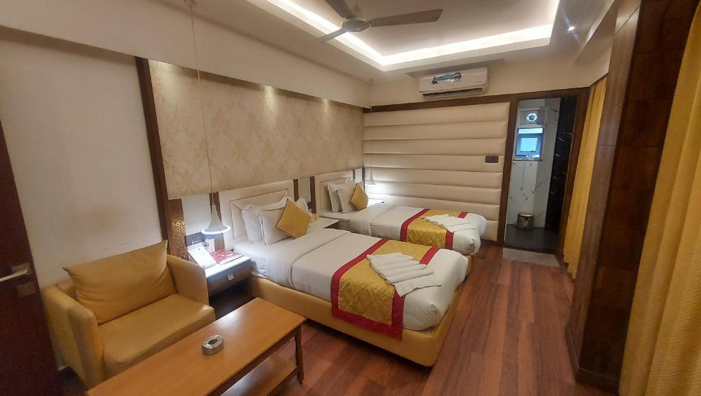 a small room with two beds and a chair at Hotel Manila in Siliguri