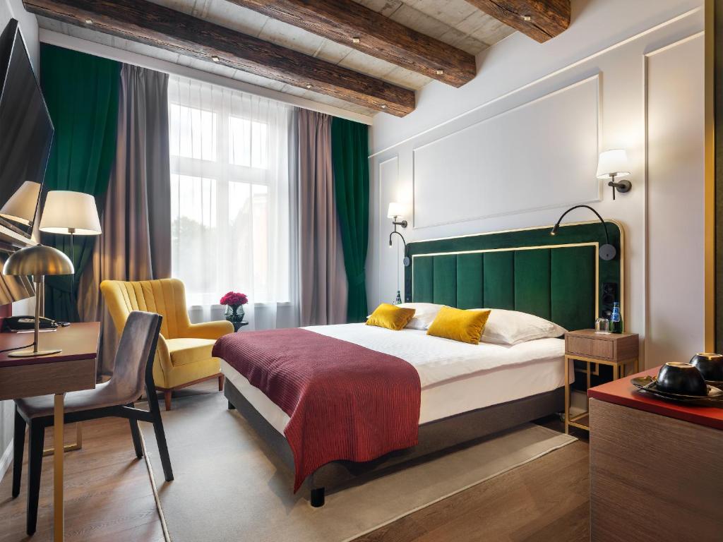 a bedroom with a bed and a desk and a chair at Hotel Golden Queen in Kraków