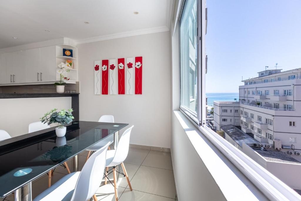 cocina con mesa y sillas y ventana grande en Perfect Beachfront Apartments, en Ciudad del Cabo