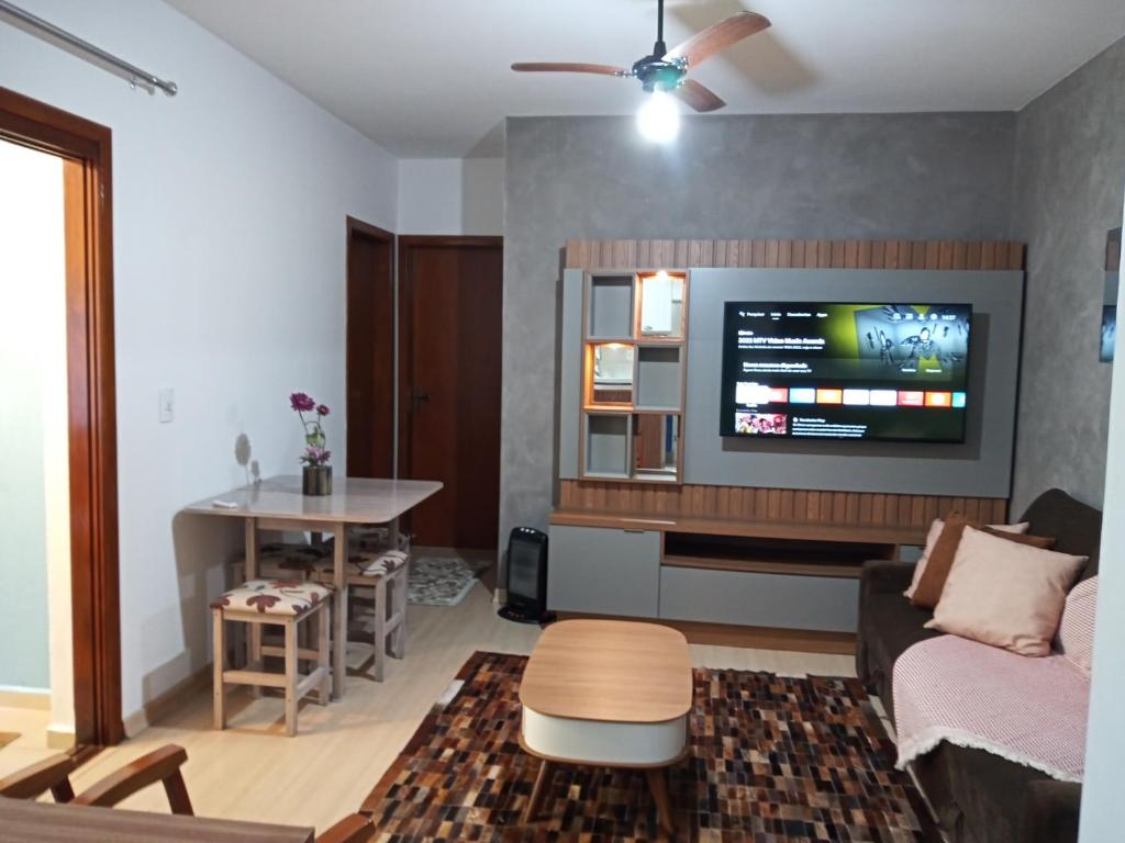 a living room with a couch and a tv on a wall at Apto Sol Poente in Canela