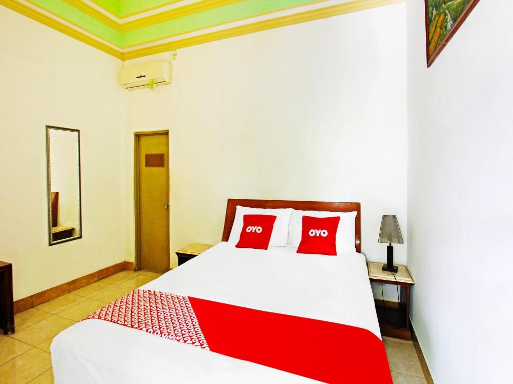 um quarto com uma cama com almofadas vermelhas em OYO 91564 Ayodya Guest House em Mataram