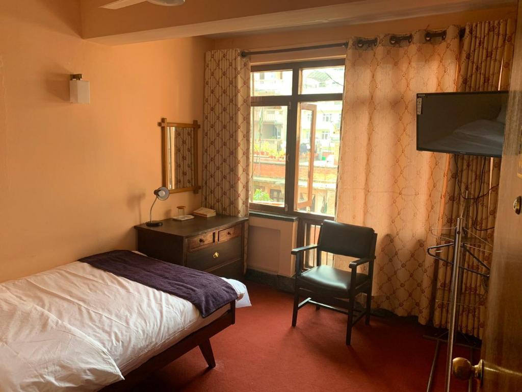1 dormitorio con cama, escritorio y ventana en Lhasa Guest House, en Katmandú