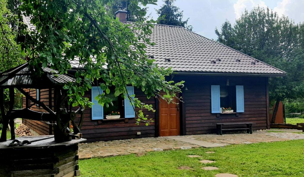 une maison bleue avec un arbre en face dans l'établissement Siedlisko Liskowate - Bieszczady, à Ustrzyki Dolne